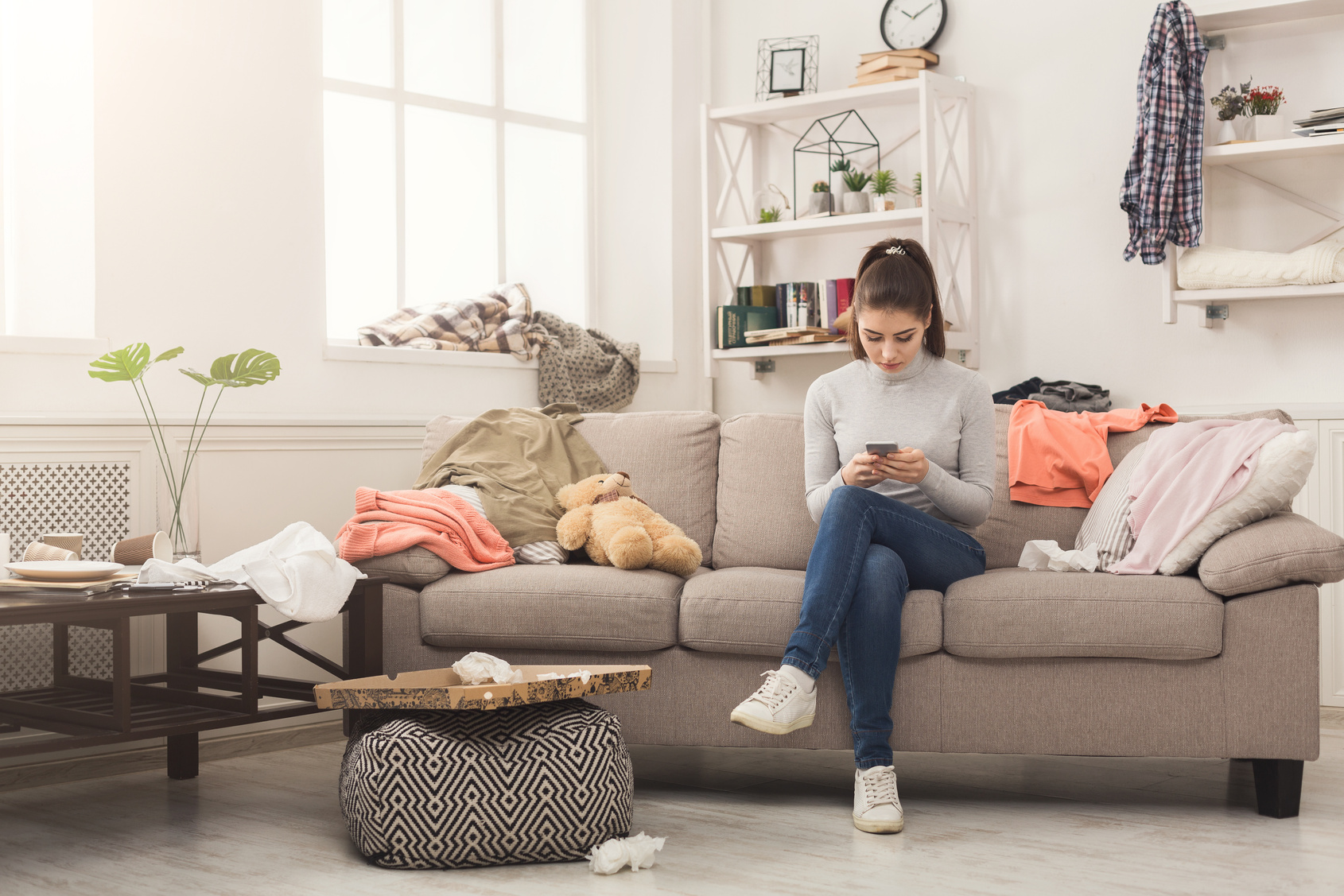 Desperate woman sitting on sofa in messy room